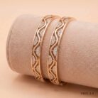 "Pair of 18k gold minimalist bangles featuring a wave cut-out design with small stones, size 2.5, by OVJ Jewels."