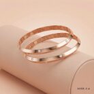 Two 18k rose gold minimalist bangles with flush-set stones and geometric inner detailing, size 2.6, by OVJ Jewels.